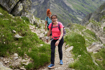 Naklejka na ściany i meble Women hiking on a trail in the rocky mountains