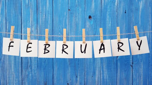 February word. February month. The inscription on the cards on a wooden blue background. Winter and frost. Cold and snow. Concept of letters and text or phrase.