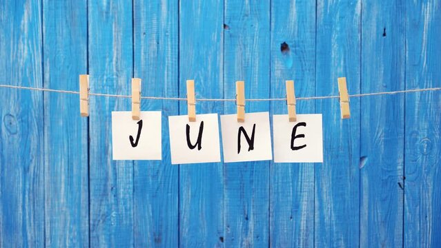 June word. June month. Letters on cards on a wooden blue background. Summer, travel, vacation, vacation. Concept of letters and text.