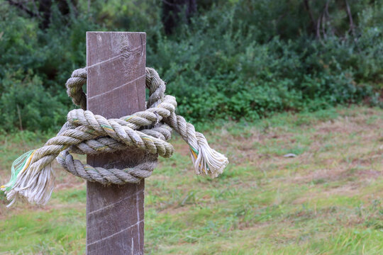 knotted rope on a fence post in field