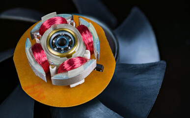 Closeup of electric motor stator with electronic coils and ball bearing on black background. Red...