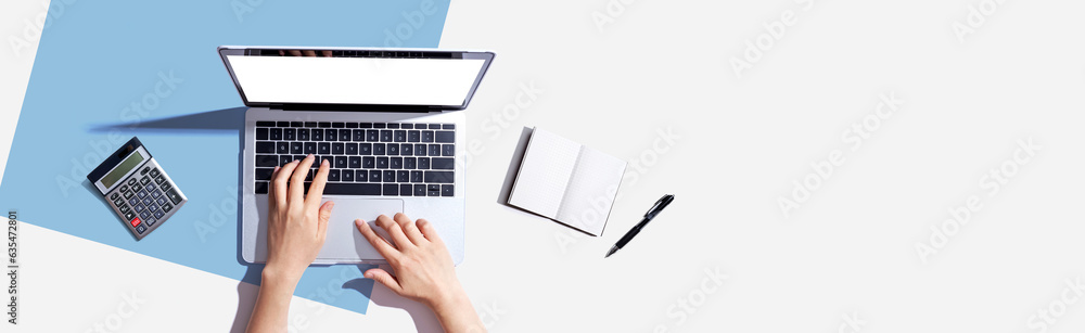 Poster person using a laptop computer with a notebook and a calculator