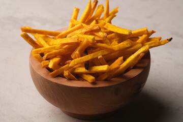 taro chips on wooden bowl. made from taro which is chopped long, seasoned, then fried. stik keripik talas. 