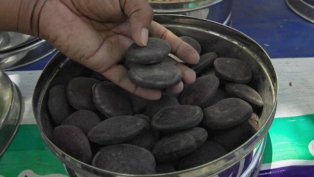 A man checks the quality of dry yongchak maru, parkia seeds, or big brown seeds