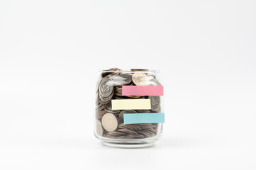 Many coins in a bottle with notepad isolated on white background , saving money for future , loan investment concept