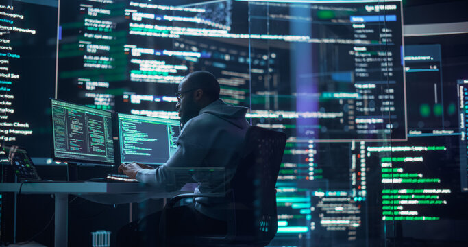 Shot of a Man Working as a Developer, Surrounded by Big Screens Displaying Lines of Code in a Monitoring Room. Black Male Programmer Using Desktop Computer, Analysing Data, Creating AI Software