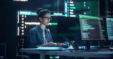 Female Programmer Working in Monitoring Control Room, Surrounded by Big Screens Displaying Lines of...