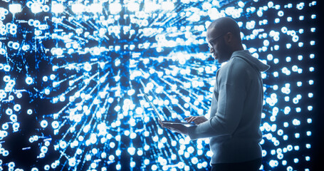 Portrait of Young Black Man Working on Laptop, Looking at Big Digital Screen Displaying Neural Network Visualisation in 3D. Professional Data Specialist Analysing User Information Concept.
