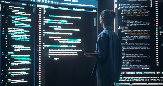 Shot of Female Programmer Working in a Monitoring Control Room, Surrounded by Big Screens Displaying Lines of Programming Language Code. Portrait of Woman Creating a Software, Coding