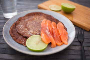 Healthy breakfast of pieces of salted smoked salmon with buckwheat pancakes and lime