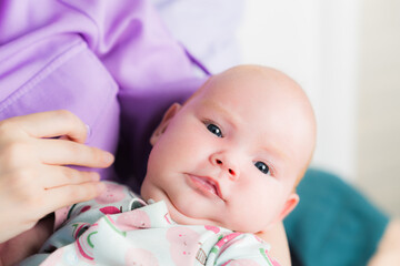 Portrait of a newborn baby girl in her mother's arms.