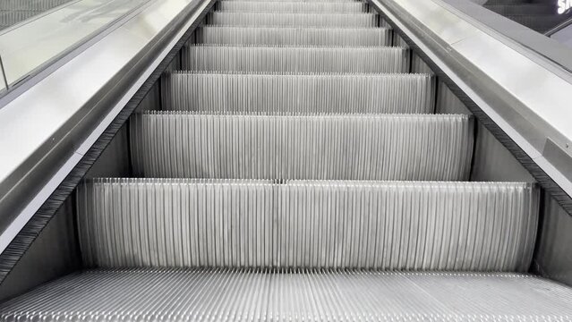Escalator steps move up and down. Metal tupes of a modern escalator in a shopping mall.