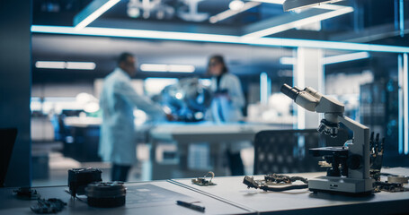 Workplace with a Modern Digital Microscope in a Research and Development Facility. Two Engineers or Scientists Working in High Tech Laboratory with Modern Equipment in the Background