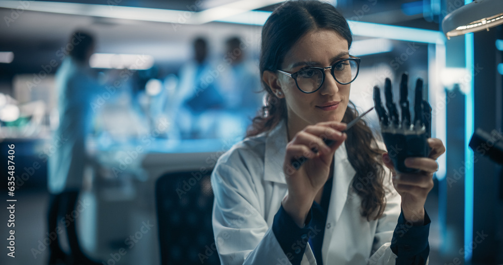Poster beautiful young female scientist working on a prosthetic robotic hand. on background diverse team of