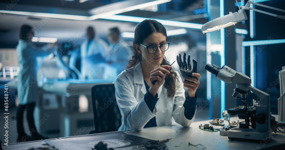 Aufkleber Female Engineer Fixing a High-Tech Bionic Hand Component. On Blurred Background Industrial Robotics Specialists in Lab Coats Working on a Mobile AI Robot in a Tech Factory Facility