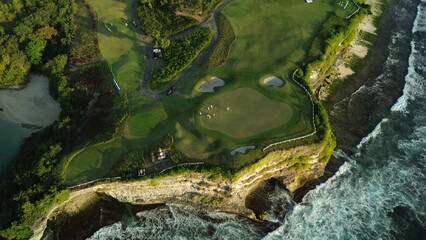Drone footage of a group of people playing golf at a country club perched on a cliff by the ocean....