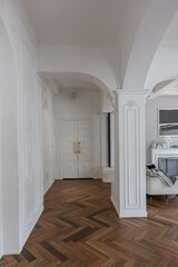 a chic expensive bright interior of a huge living room in a historic mansion with arched arches, columns and white walls decorated with ornaments and stucco.