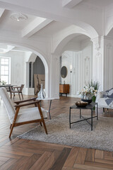 a chic expensive bright interior of a huge living room in a historic mansion with arched arches, columns and white walls decorated with ornaments and stucco.