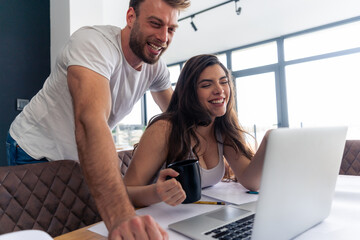 Young married couple using laptop while looking for a place to travel, pointing finger at laptop