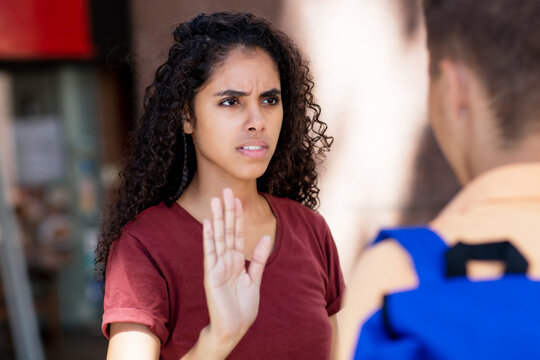 Latin american woman gesturing stop and rejecting young adult man