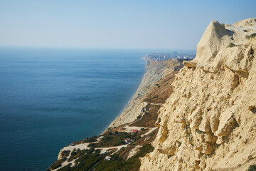 Landscape of a high rocky shore by the sea. There is a big city in the distance