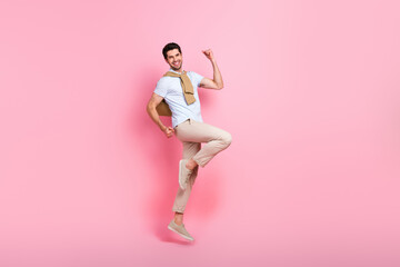 Full size profile portrait of delighted cheerful man jumping raise fists empty space isolated on pink color background