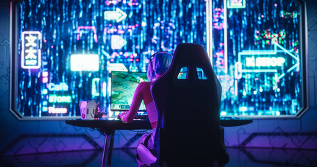 Female Gamer Playing Fantasy Strategy Video Games Online on a Computer. Stylish Girl Wearing Headphones and Playing with Friends and Players. Photo from the Back