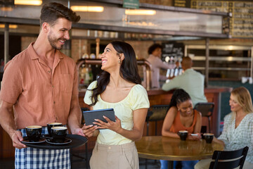 Portrait Of Female Manager With Digital Tablet And Waiter Working In Restaurant Or Coffee Shop