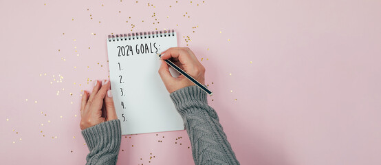 New Year goals 2024. Woman's hand writing in notebook goals list. Concept of new year planning....