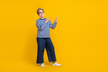Fototapeta na wymiar Full length photo of cheerful pensioner wear trendy jeans clothes two arm presenting offer empty space isolated on yellow color background