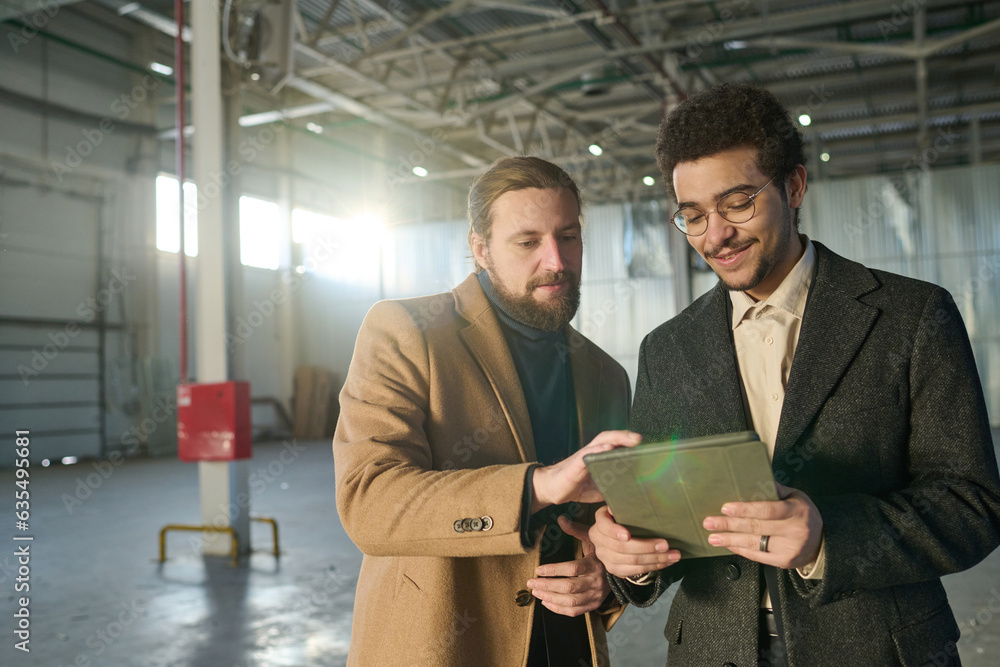Aufkleber two young intercultural entrepreneurs in formalwear discussing sketch on tablet screen while one of 