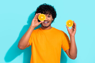 Photo portrait of young excited funky guy promotion fresh healthy orange fruit cover eye vitamins...