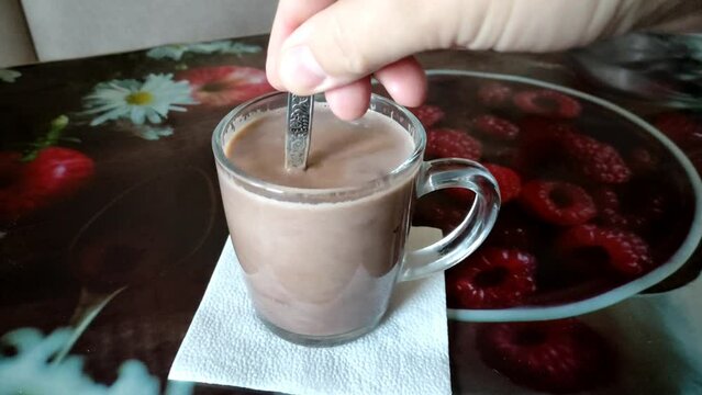 Stirring with a spoon of cocoa in a transparent mug, 4K video