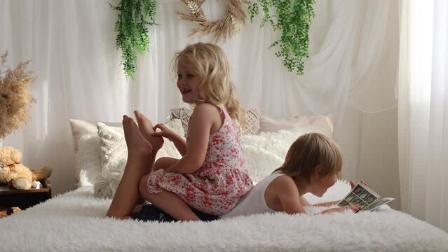 Cute sweet toddler children, tickling feet on the bed, laughing and smiling, childish mischief, happiness