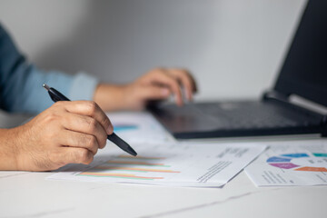 The astute business analyst is meticulously dissecting revenue graphs on the workstation, while...