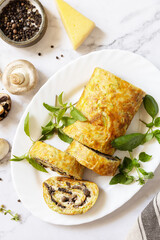 Vegetarian delicious food. Zucchini roll (roulade) with cheese and mushrooms on a marble tabletop. View from above.