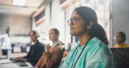 Portrait of a South Asian Female Student Studying in College with Diverse Classmates. Indian Girl Listening to Teacher, Using Computer to Apply Her Knowledge to Acquire New IT Skills in Class