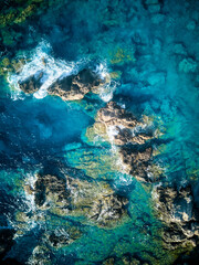 Vista aérea de olas con rocas en agua turquesa