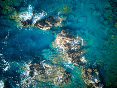 Vista a&eacute;rea de olas con rocas en agua turquesa