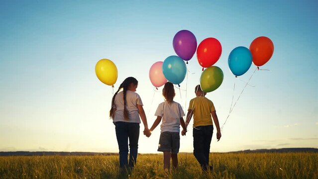 children in balloons in the park. children walk in nature in park with balloons. happy family kid holiday concept. children view from back silhouette walk in nature at sunset dream holding balloons