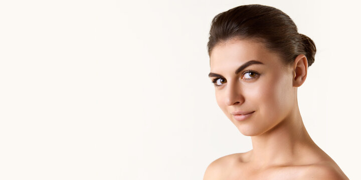 Beautiful young woman with well-kept healthy skin, brown hair and eyes looking at camera against white studio background. Concept of female beauty, skin care, cosmetology and cosmetics, health, ad