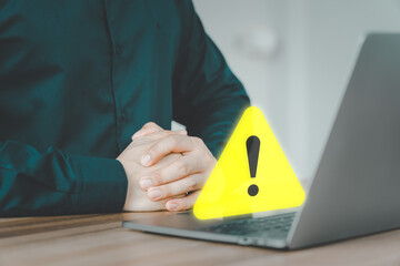 User man using a computer laptop with triangle caution warning sign for notification error. Concept technology of computer virus detected, personal data protection, network security and maintenance.