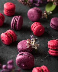 pink and purple french macaroon cookies with lilac flowers on a dark background.