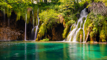 Panoramic view of waterfall and cascades in natural reserve in Plitvice, Croatia on a sunny summer day with longtime exposure. Colorful scenery with clear turquoise water. Popular tourist attraction.