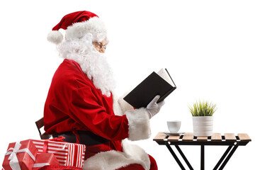 Santa Claus sitting at a coffee table and reading a book