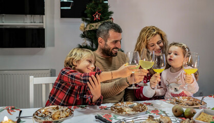 happy family with little kids toasting at christmas dinner, happy celebrate new year