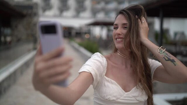 Plano cercano en 4k de chica haciendo video llamada desde su smartphone en piscina de hotel de lujo