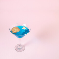 Martini glass with shell and starfish on pink background. Creative concept.