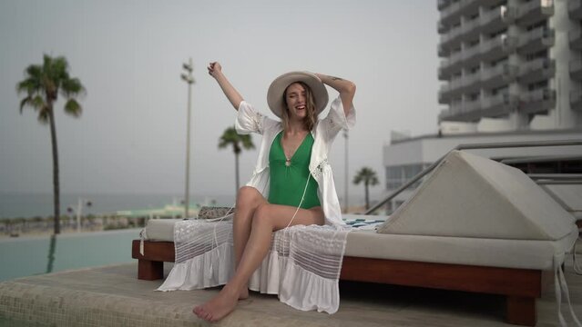 Chica joven en hamaca de piscina de hotel leyendo y disfrutando de las vacaciones