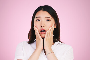 Surprise, wow and hands on woman face in studio with anxiety for fake news, drama or secret on pink background. Omg, portrait and Japanese female model shocked by gossip, announcement or emoji info